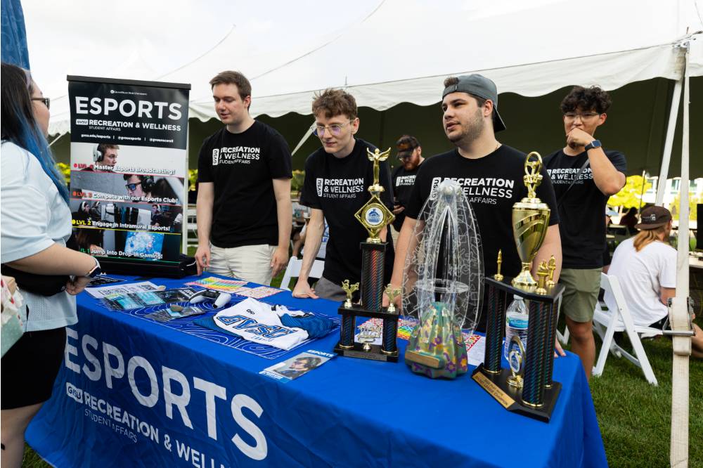 students standing at table with ESPORTS tablecloth